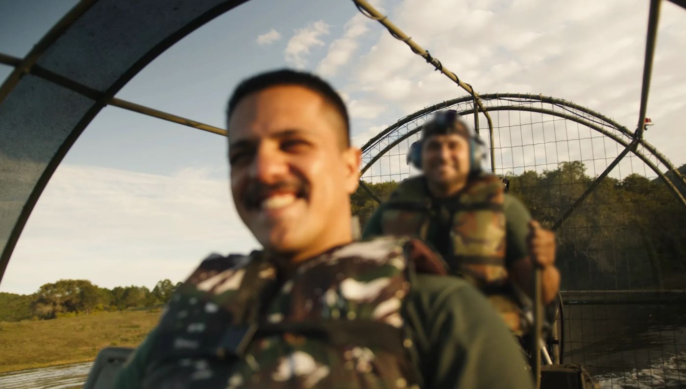 Visitante sorrindo a bordo do aerobarco com colete camuflado