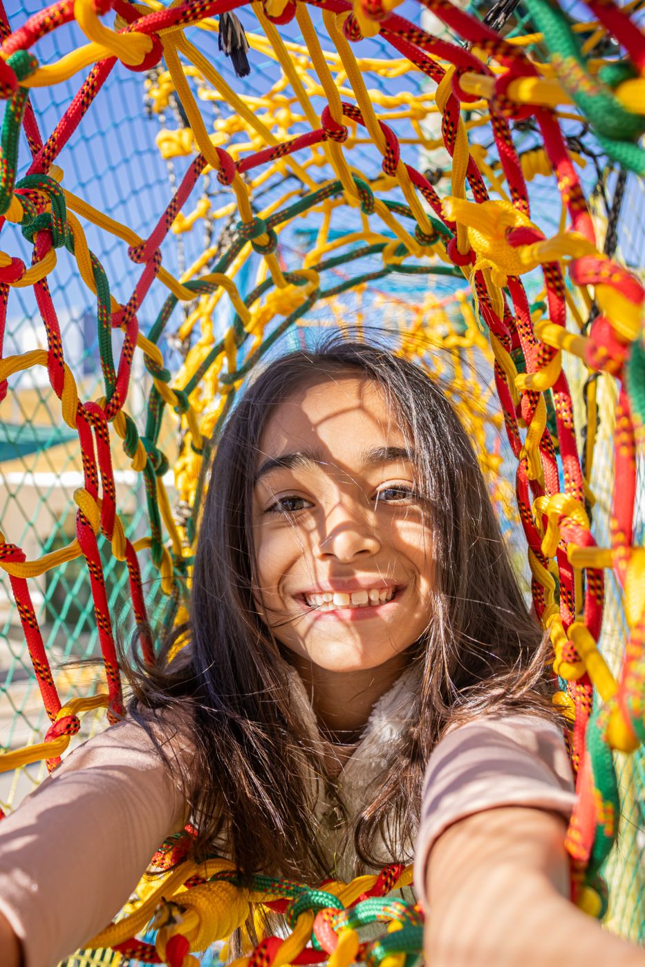 Menina sorrindo dentro do túnel de cordas coloridas do Arvorismo do Dudinha